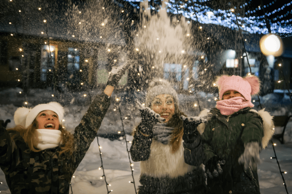 Mother and two daughters throwing snow in the air.