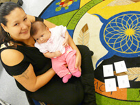 Indigenous mother sitting on a colourful carpet holding her baby looking up at camera