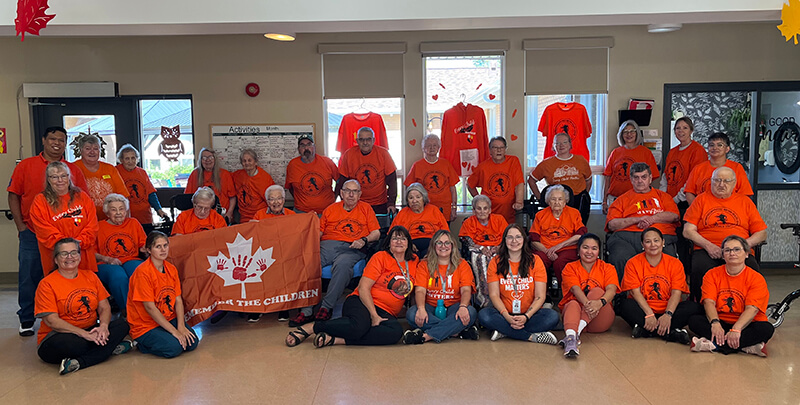 Group of Staff and Residents at Russell PCH wearing orange shirts.