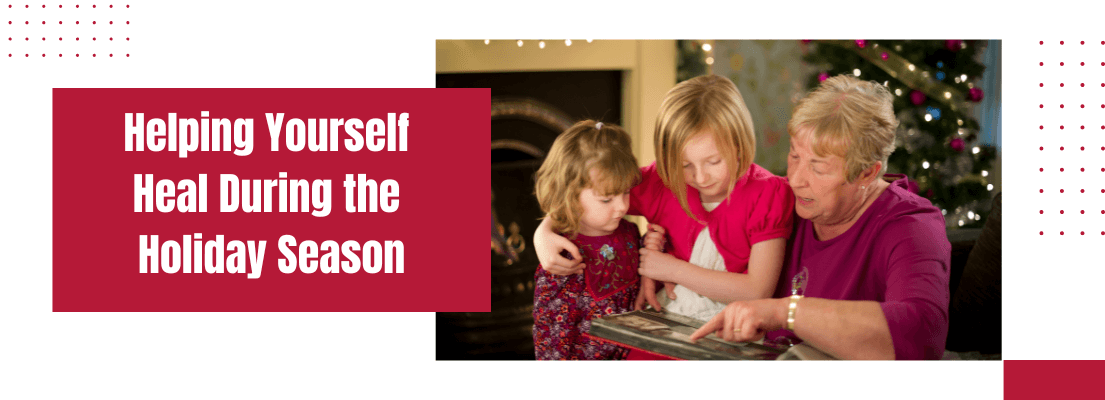 Grandmother showing granddaughters photographs beside the Christmas tree.